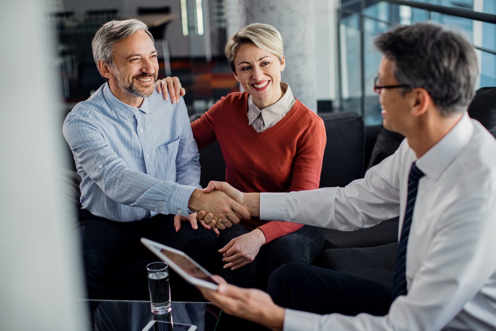 Happy couple came to an agreement with their insurance agent in Happy couple handshaking with financial advisor after successful meeting in the office.